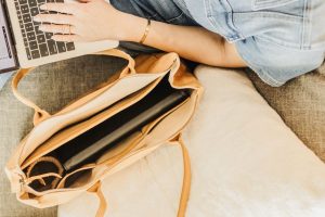 Stylish leather tote bag on couch with a laptop, perfect for work and travel.