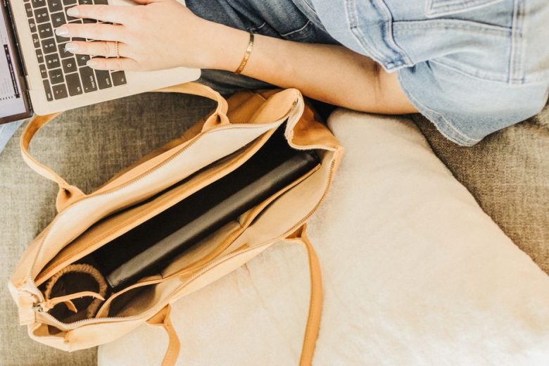 Stylish leather tote bag on couch with a laptop, perfect for work and travel.