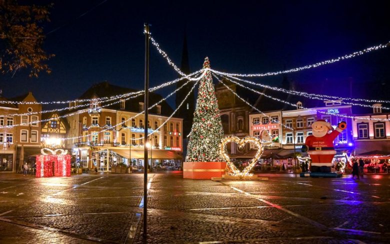 A festive night scene at Sittard's Christmas market with lights and decorations.